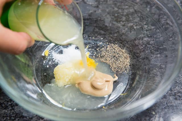 Pouring Lemon Juice into Bowl with Mustard, Salt, Pepper, and More