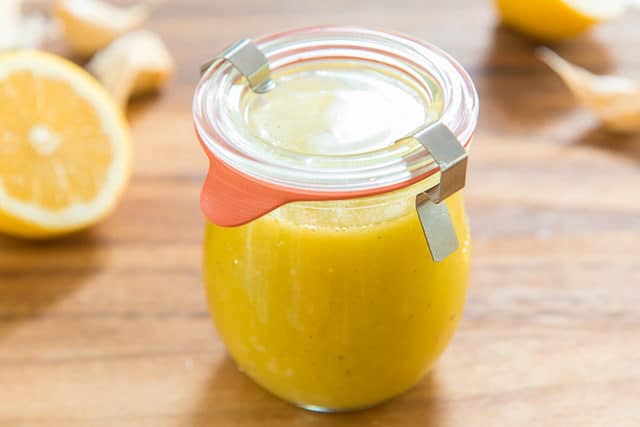 Lemon Vinaigrette Dressing Recipe - Stored in Glass Jar with Lemon and Garlic in Background