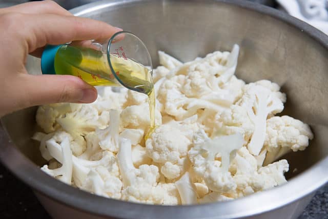 Pouring Olive Oil Into a Bowl with Cauliflower Florets