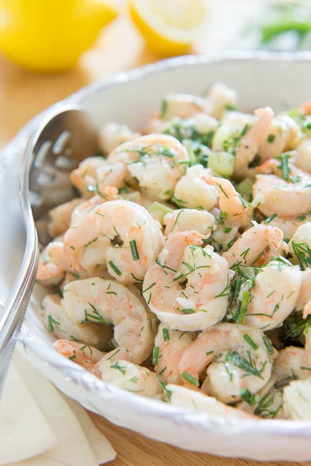 A big white bowl filled with shrimp salad studded with celery and dill