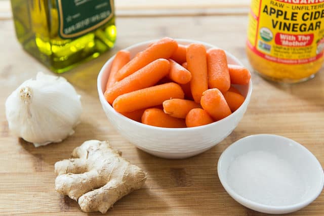 Baby Carrots, Ginger Root, Garlic, Olive Oil, Apple Cider Vinegar, and Salt on Wooden Board