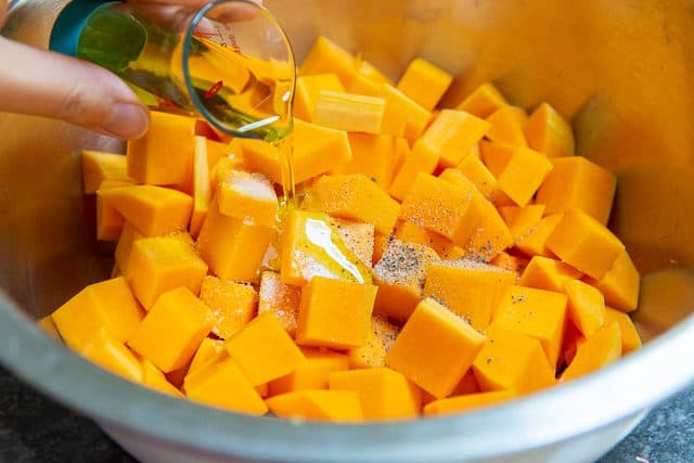 Adding Oil and Seasoning to Butternut Squash Cubes in Mixing Bowl