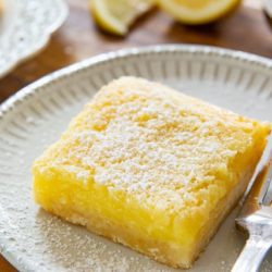 Lemon Bars On White Plates with Fork and Powdered Sugar Dusting