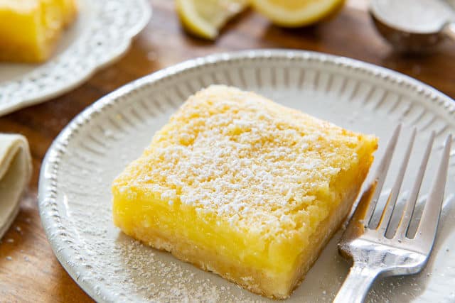 Lemon Bars Recipe - Plated on White Dishes with Fork and Confectioner\'s Sugar Dusting
