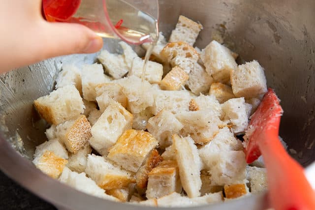 Pouring Oil over Bread Cubes in Bowl