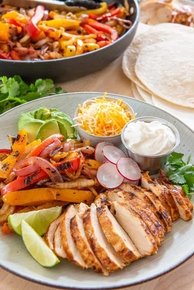 Chicken Fajitas - On a Plate with Cheese, Sour Cream, and Lime Wedges