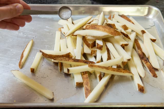 Adding Salt to Unbaked Fries on Sheet Pan
