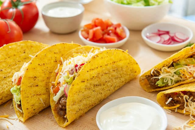 Ground Beef Taco Recipe - Served Stuffed Into Hard Shells with Tomatoes, Cheese, and Sour Cream