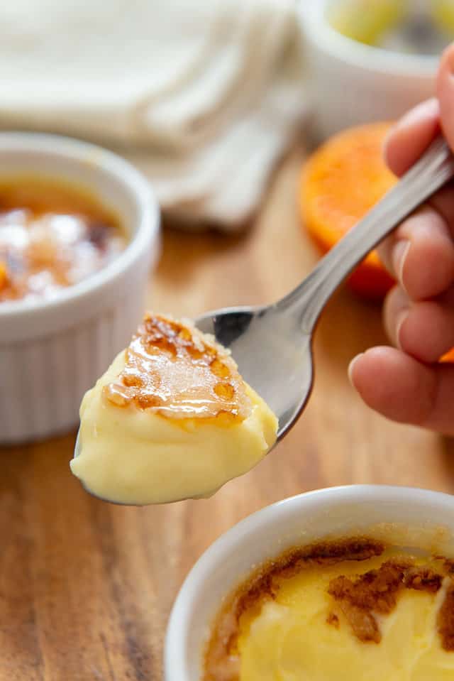 A Spoonful Held Up Of the Best Creme Brulee to show Creamy Middle