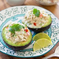 Crab Stuffed Avocado Served on Blue Plate with Lime Wedges