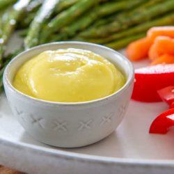 Small ramekin filled with aioli and surrounded with bell pepper, carrots, and asparagus