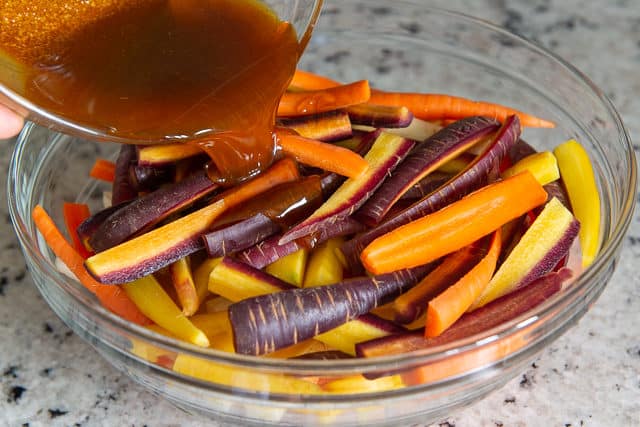 Adding Spices and Olive Oil to Rainbow Carrots in Bowl