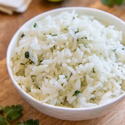 A white bowl filled with cilantro lime rice on wood cutting board