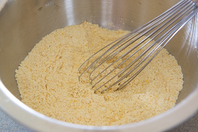 All Purpose Flour, Yellow Cornmeal, Baking Soda, and Salt Mixed In a Bowl with a Whisk