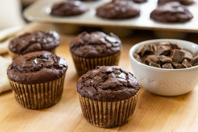 Chocolate Muffin Recipe - Presented On a Wooden Board with Bowl of Chocolate Chips and a Napkin