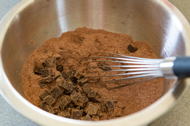 Sifted Cocoa and Flour in Mixing Bowl with Chocolate Chunks and a Whisk