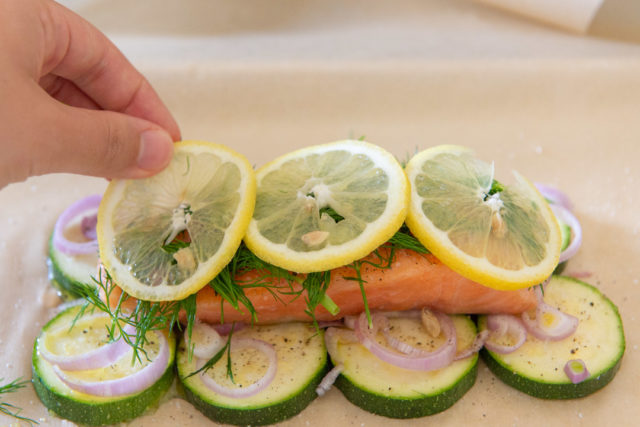 Adding Lemon Slices On Top of Baked Salmon En Papillote with Zucchini Slices