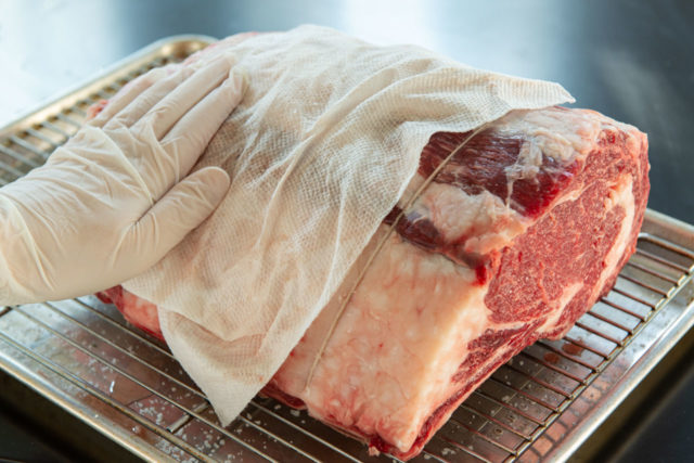 Blotting an Overnight Salt Rested Beef Standing Rib Roast with paper Towel