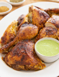 Peruvian Chicken - Cut Into Pieces on White Platter with Green Sauce