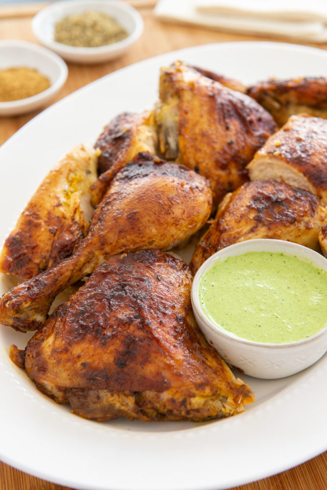 Peruvian Chicken - Cut Into Pieces on White Platter with Green Sauce