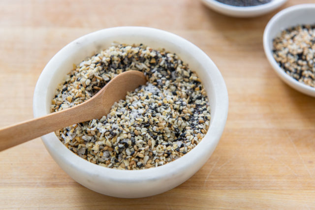 Everything Bagel Seasoning Recipe - Shown in A White Dish with Wooden Spoon
