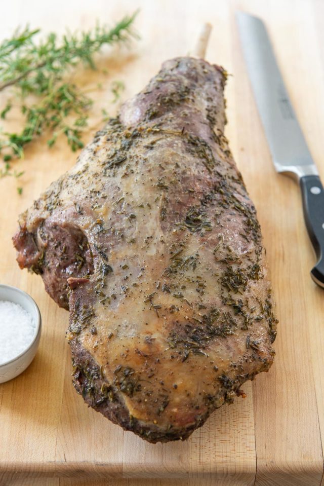 Bone In Leg of Lamb - On a wooden Board with Herbs