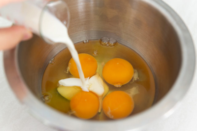 Pouring Half and Half Into Bowl with Four Eggs