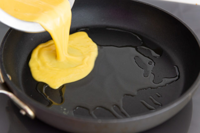 Adding the eggs to a hot skillet with ghee