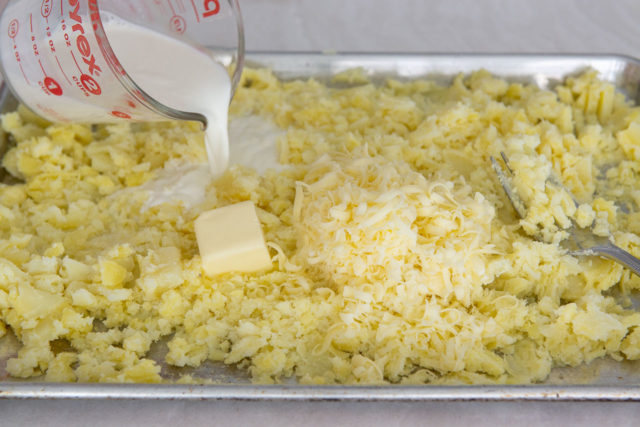 Pouring Half and Half Over Mashed Potatoes with Butter and Cheddar Cheese