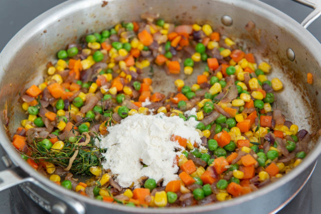 All-purpose flour added to vegetables in stainless steel skillet