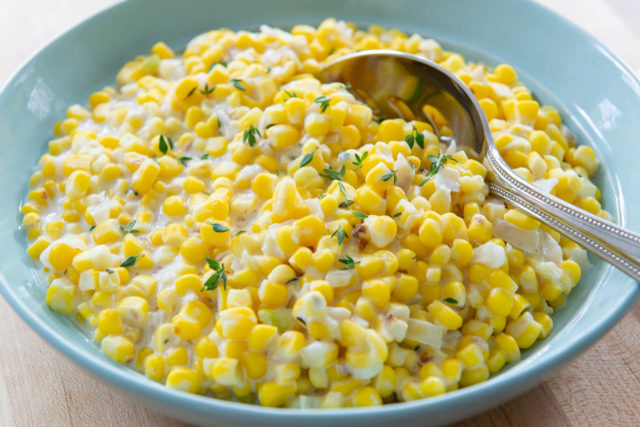 Creamed Corn Recipe - Served in a Bowl Bowl with Serving Spoon and Thyme Leaves