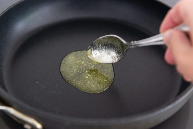 Pouring Ghee Into a Skillet with a Spoon
