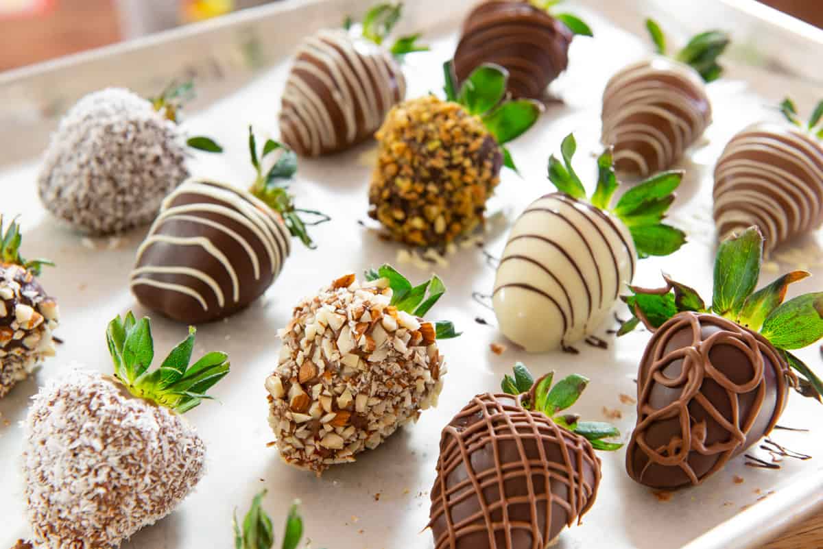 Chocolate Covered Strawberries Recipe Presented on Wax Paper with chocolate Drizzles and Nuts