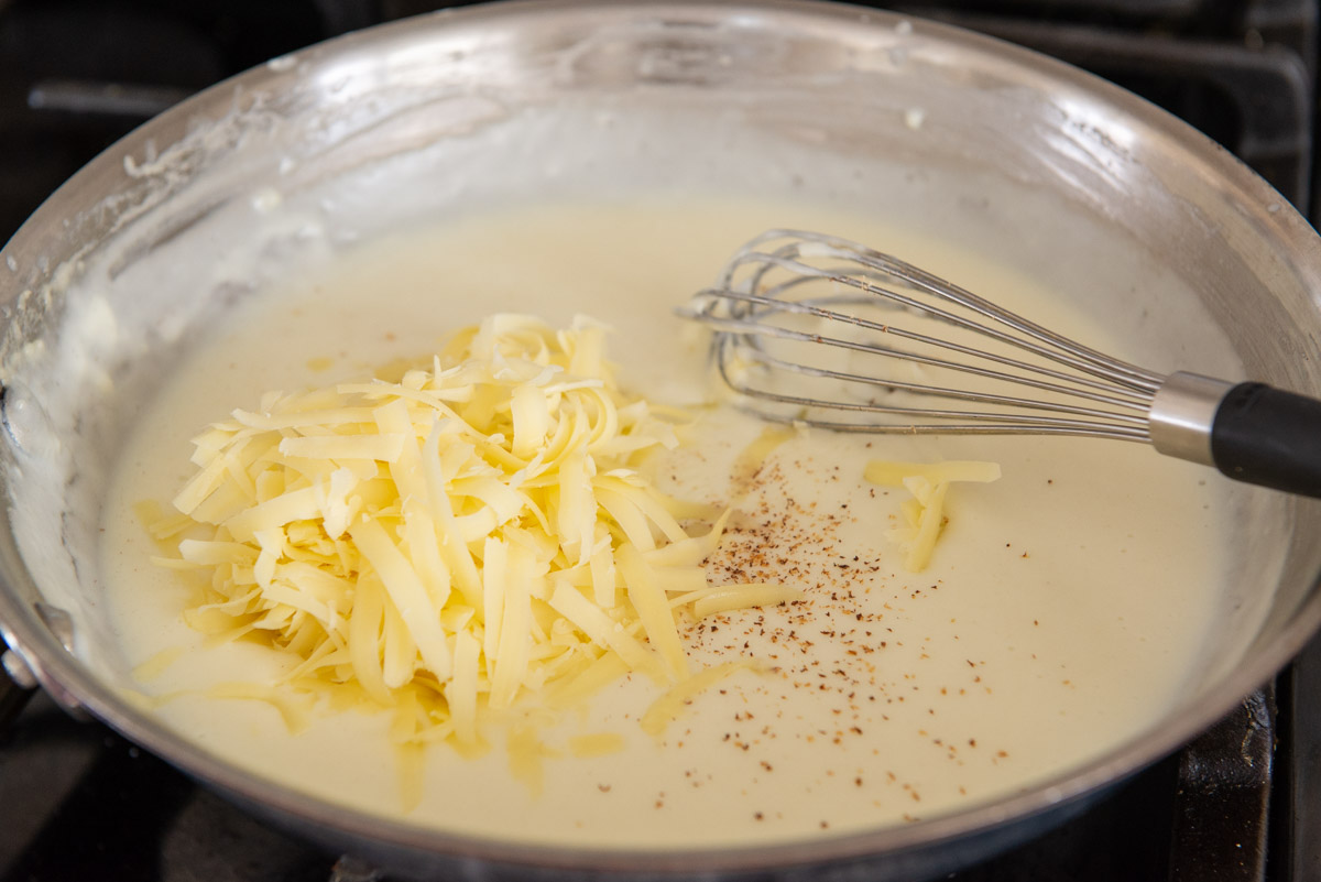 Grated Gruyere Cheese Added to Bechamel Sauce in Skillet