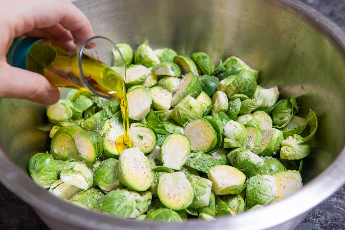 Pouring Olive Oil on Halved Brussel Sprouts in Bowl