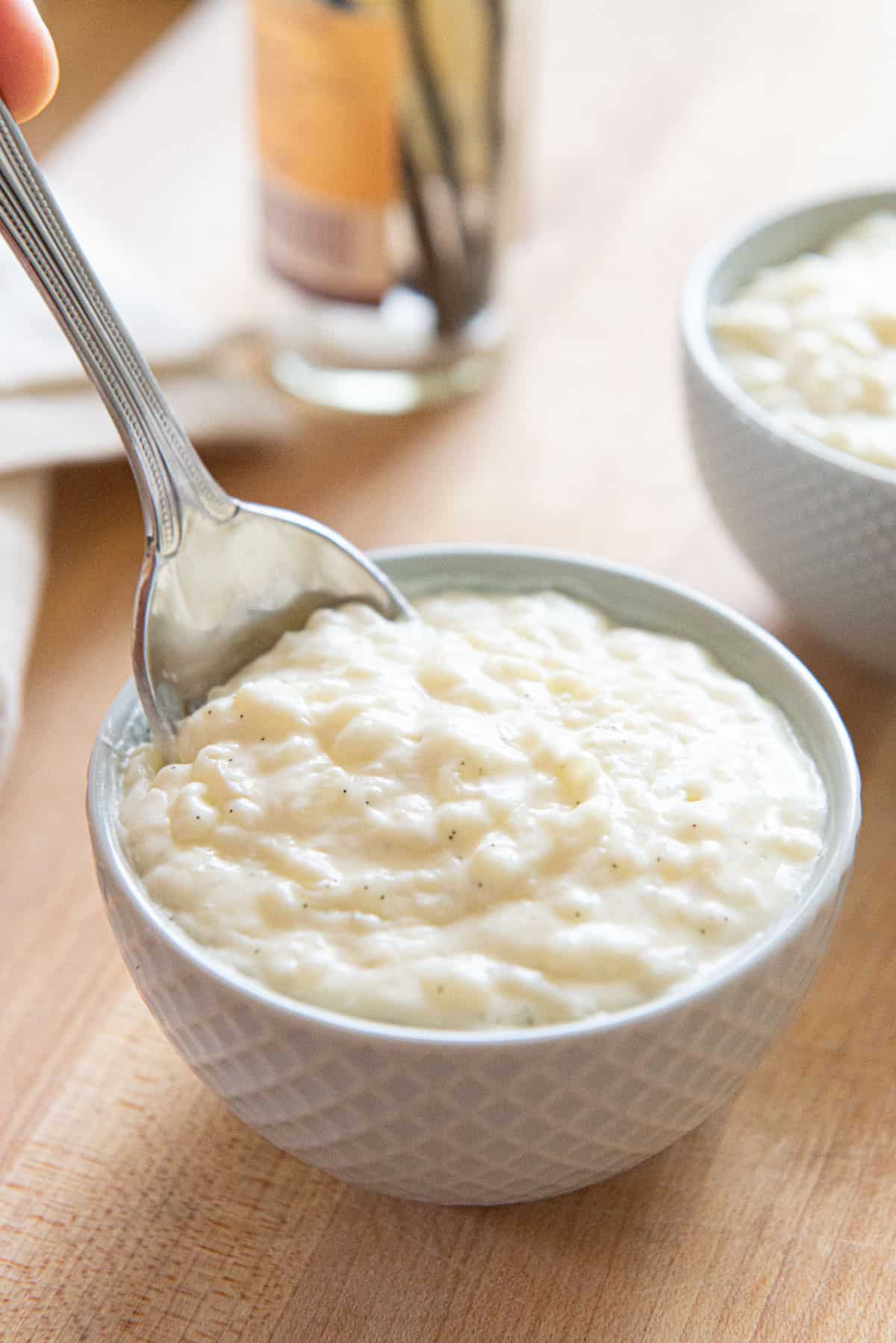 Rice Pudding Recipe Served in Small blue Bowls with Spoon Scooping