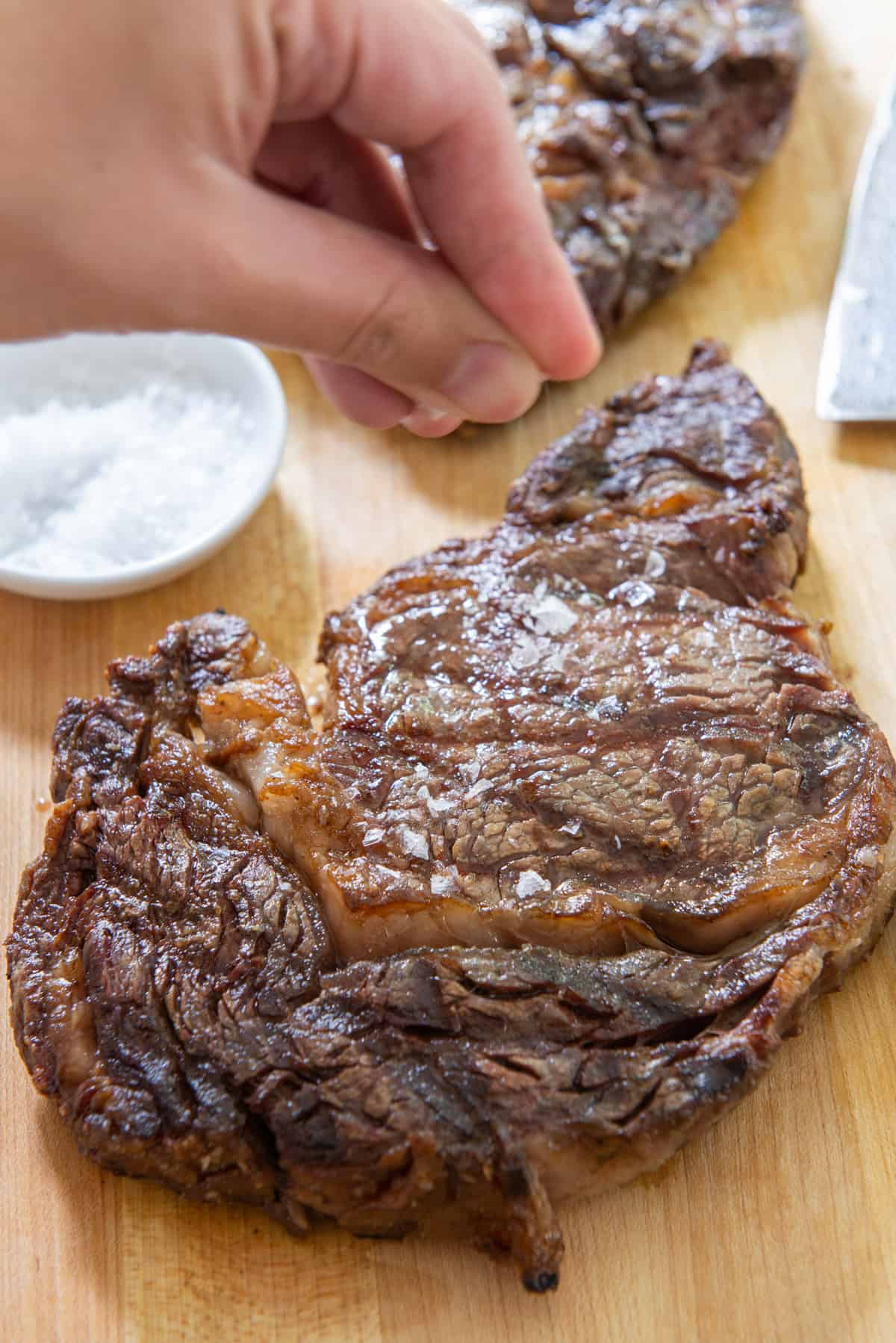 Sprinkling Salt on a Grilled Ribeye Steak