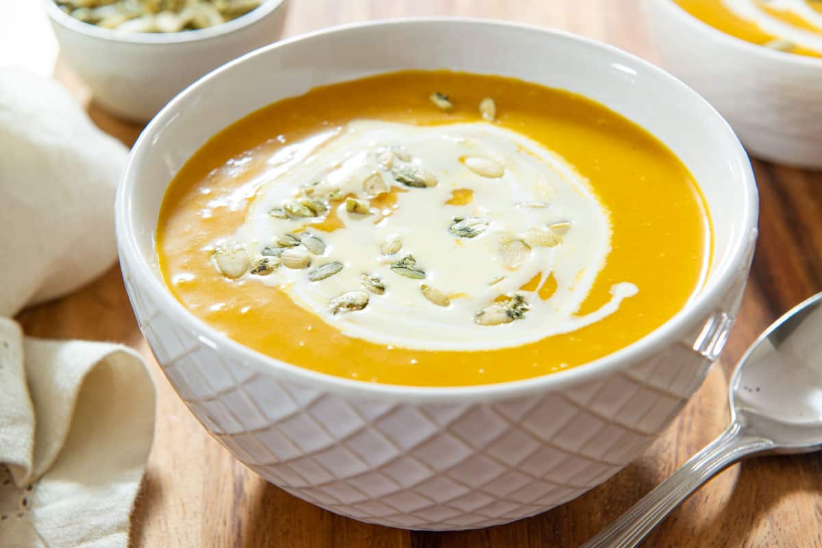 Butternut Squash Soup Recipe Served in White Bowl with Cream and Pumpkin Seeds