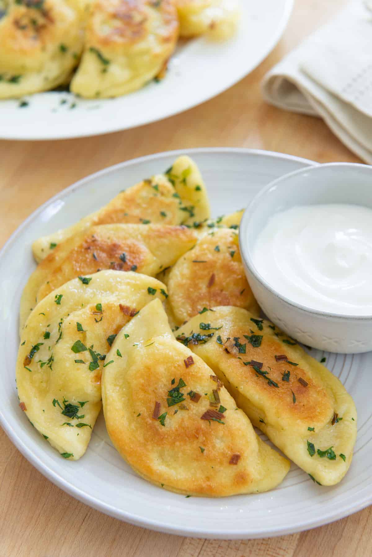 Homemade Pierogies On a White Plate with Sour Cream