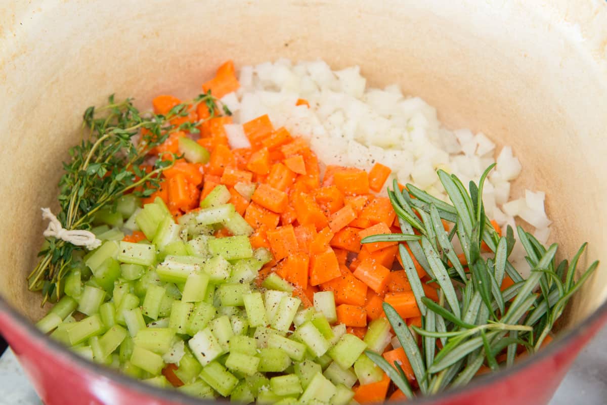 Chopped celery, carrots, onions, and herbs in pot