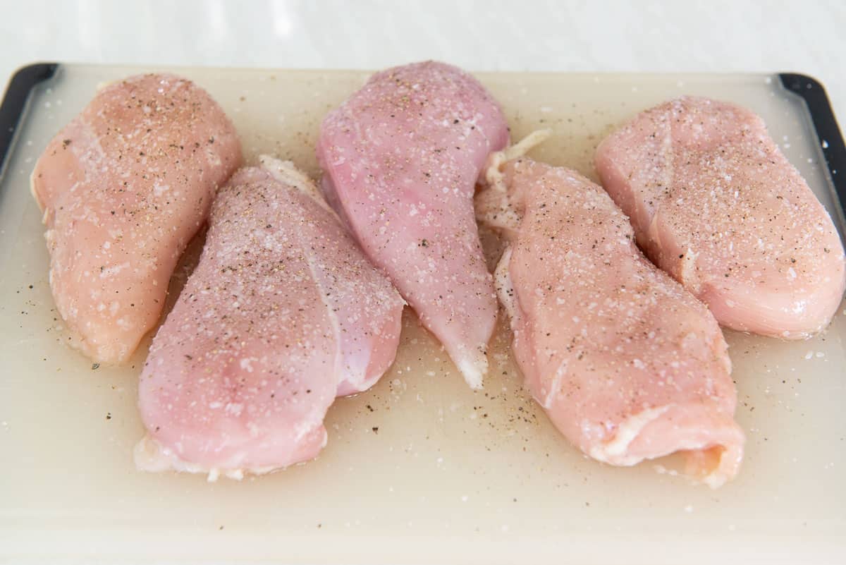 Five Breast Pieces On A Cutting Board with Salt and Pepper