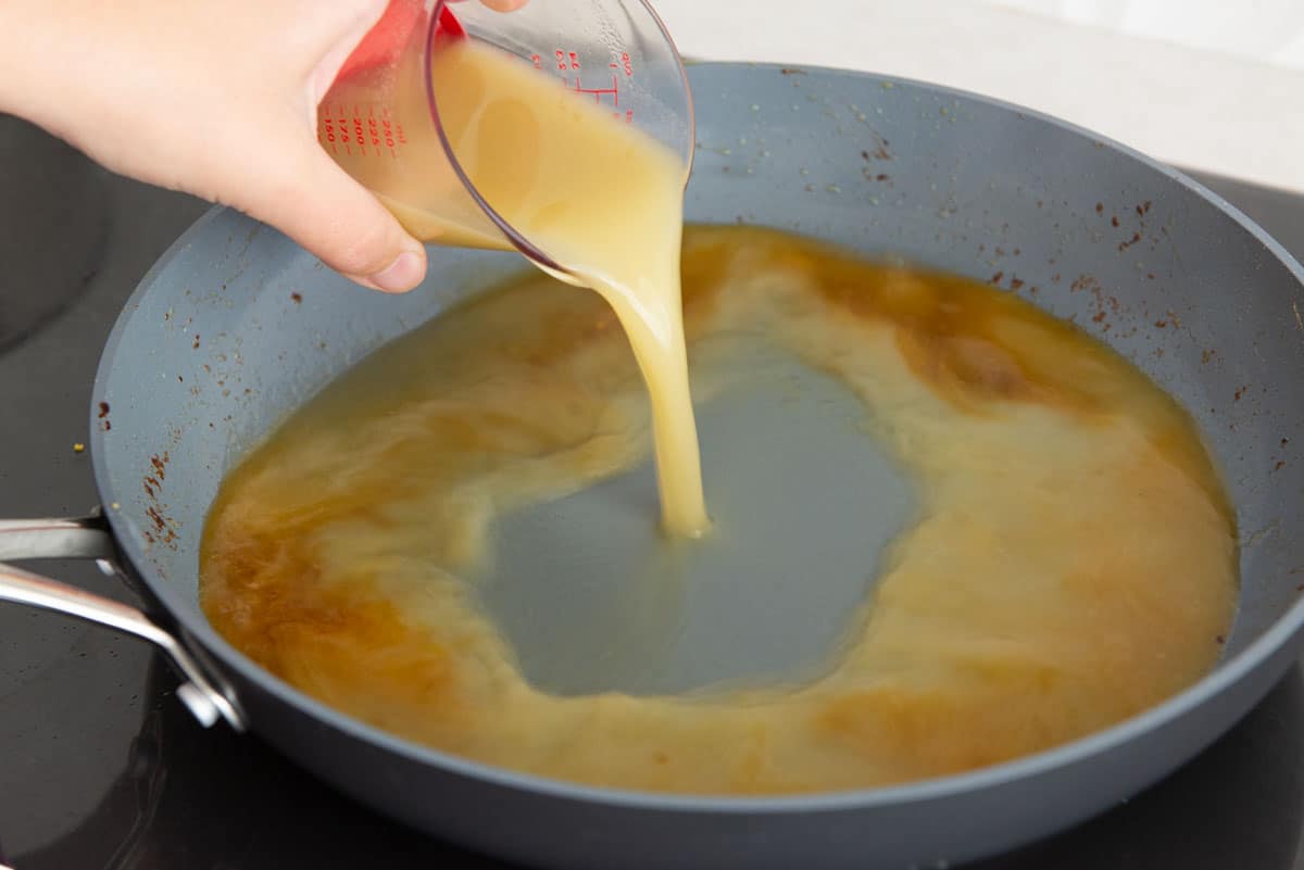 Pouring Chicken Stock Into Skillet For Reducing Sauce