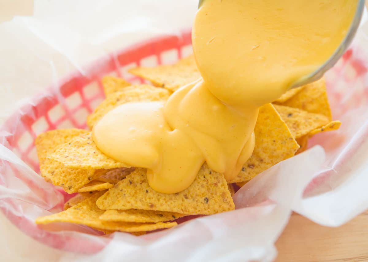 Nacho Cheese Sauce Ladled On top of Chips