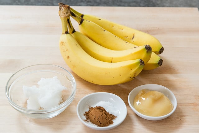 Bananas, coconut oil, cinnamon, salt, and honey on a wooden board