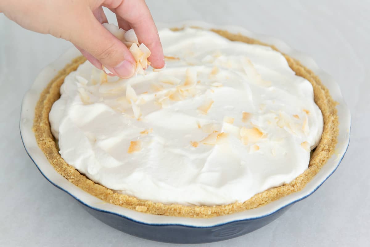 Sprinkling toasted coconut flakes on top of the coconut cream pie