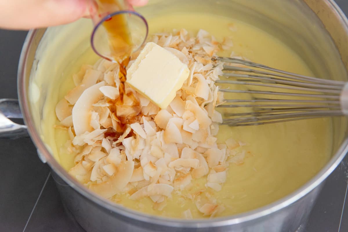 Adding coconut flakes, butter, and vanilla extract to the coconut pudding filling