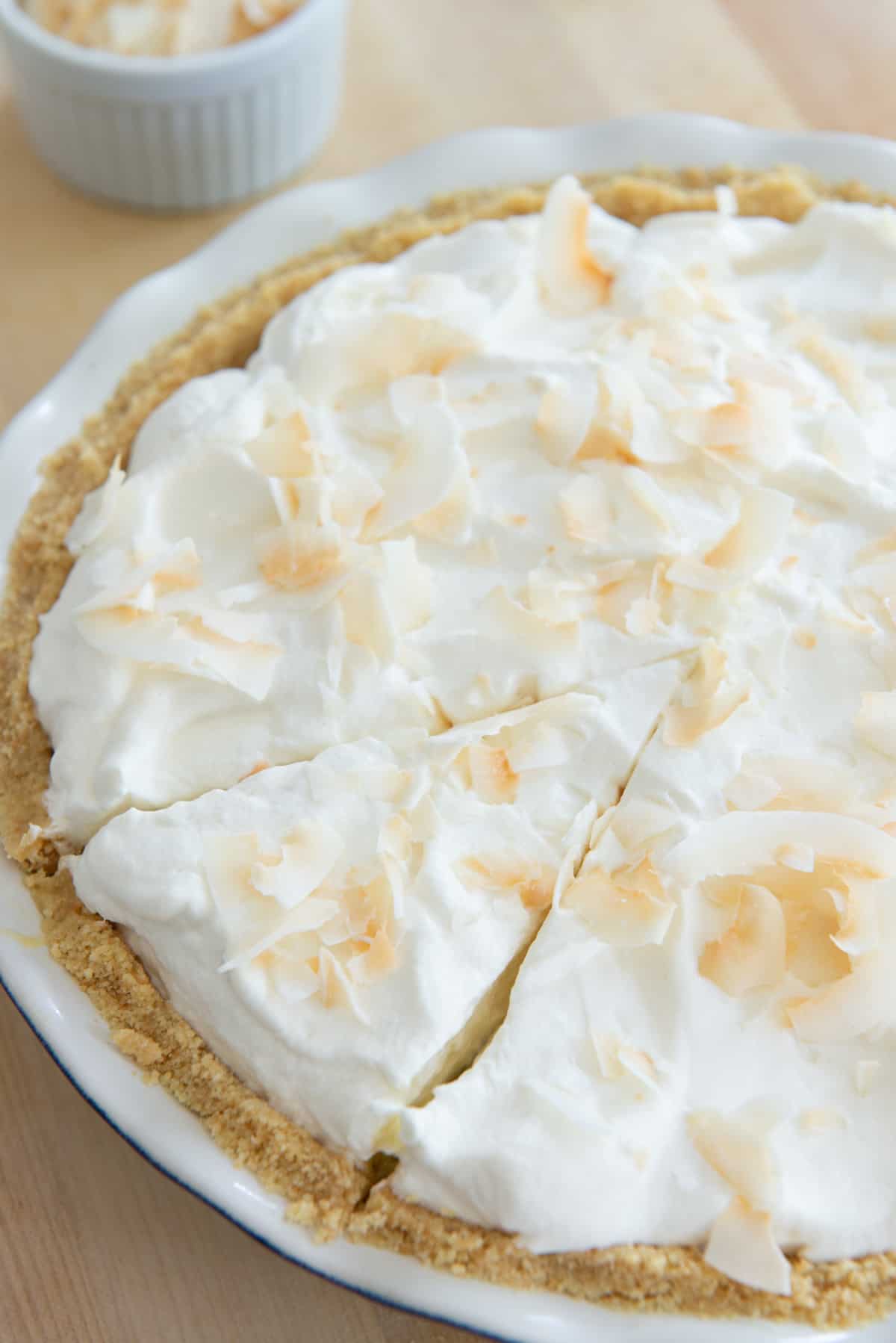 A standard size coconut cream pie with a slice cut but not removed