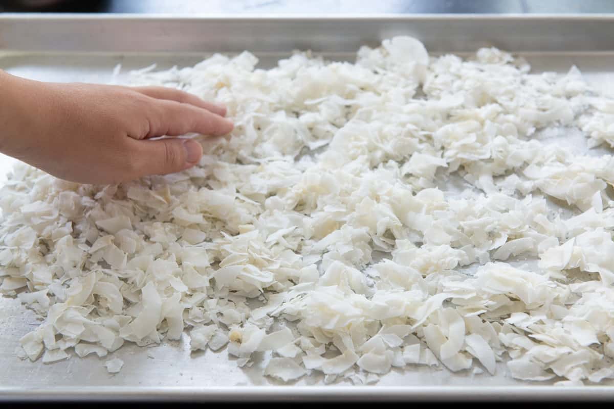 Spreading coconut flakes out on a sheet pan with hand