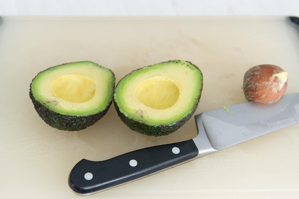 Two Avocado Halves On Cutting Board with Pit Removed