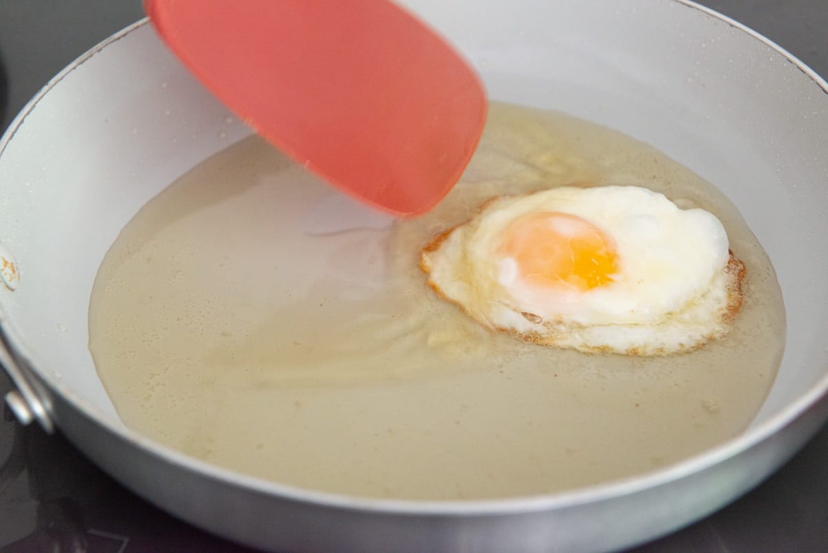 Basting an egg with bacon fat in the pan